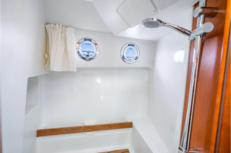 Slide: The Image of 2017 Beneteau Swift Trawler 30 bathroom with shower, portholes, and wooden accents. - 19