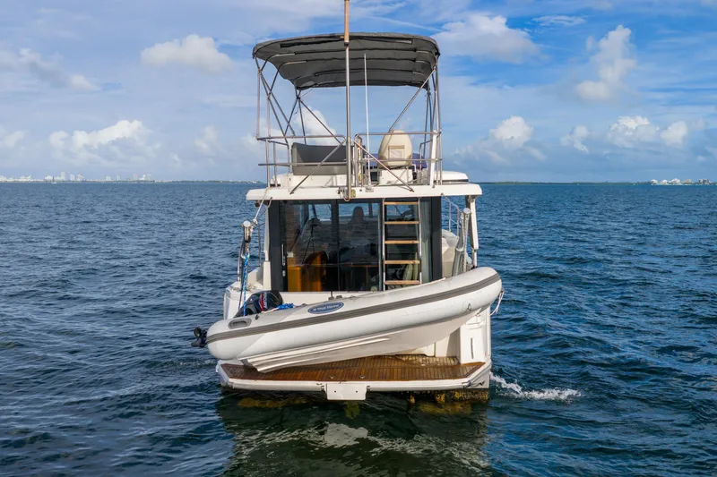 Slide: The Image of 2017 Beneteau Swift Trawler 30 on open water, rear view with inflatable boat. - 7