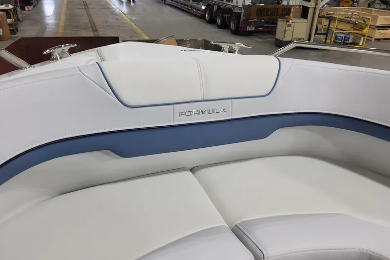 Slide: The Image of 2026 Formula 310 Bowrider OB boat interior with white and blue seating in a warehouse. - 35