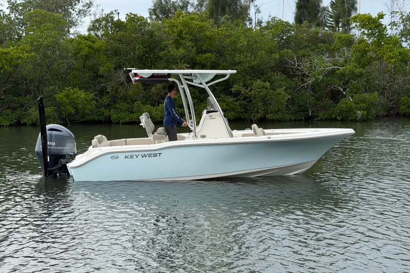 The Image of 2023 Key West 219 FS boat on calm water, surrounded by lush greenery. - 1