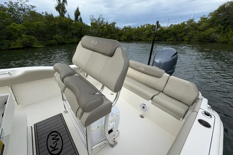 Slide: The Image of 2023 Key West 219 FS boat interior with seating and outboard motor on a calm waterway. - 16