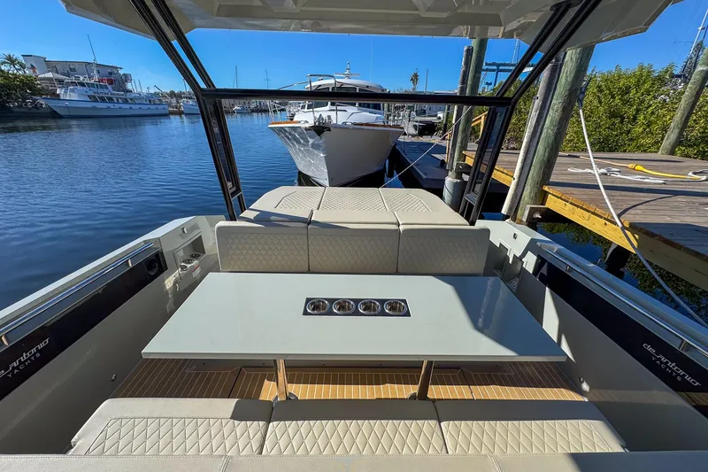 Slide: The Image of 2026 De Antonio Yachts D32 interior with seating and table, docked at marina. - 13