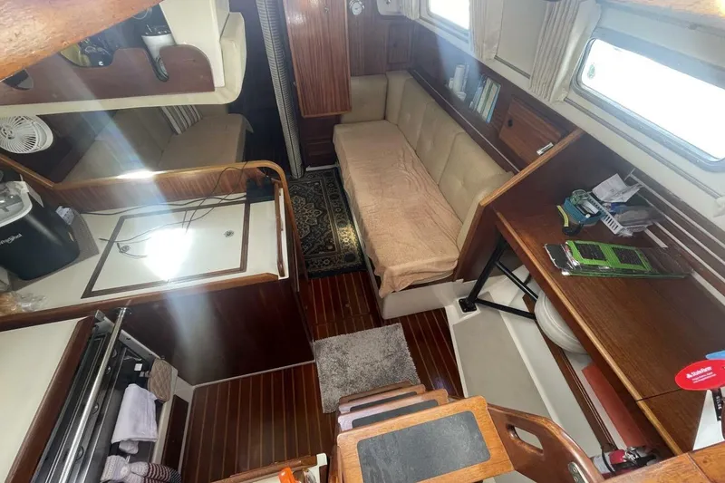 Slide: The Image of 1981 Pearson 36 sailboat interior with cozy seating, wooden cabinetry, and compact kitchen area. - 14