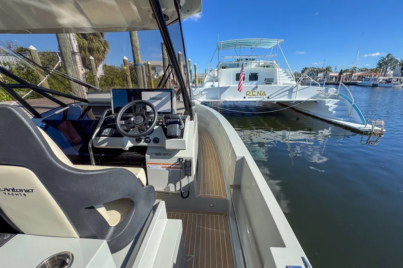 Slide: The Image of 2026 De Antonio Yachts D32 cockpit with steering wheel, docked near a white catamaran. - 19