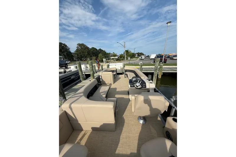 Slide: The Image of 2025 Harris Cruiser 230 pontoon boat with beige seating at a dock under blue skies. - 4