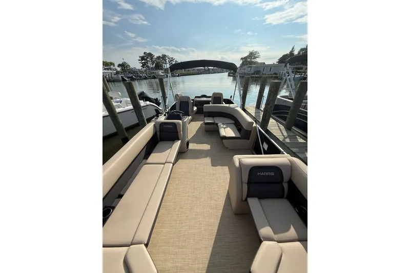 Slide: The Image of 2025 Harris Cruiser 230 pontoon boat with spacious seating, docked by a serene waterfront. - 5