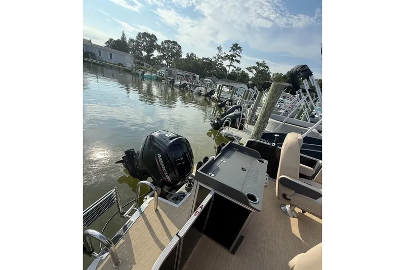 Slide: The Image of 2025 Harris Cruiser 230 pontoon boat docked, featuring a Mercury outboard motor. - 7
