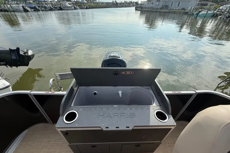 Slide: The Image of 2025 Harris Cruiser 230 boat with sink, cup holders, and scenic marina view. - 8
