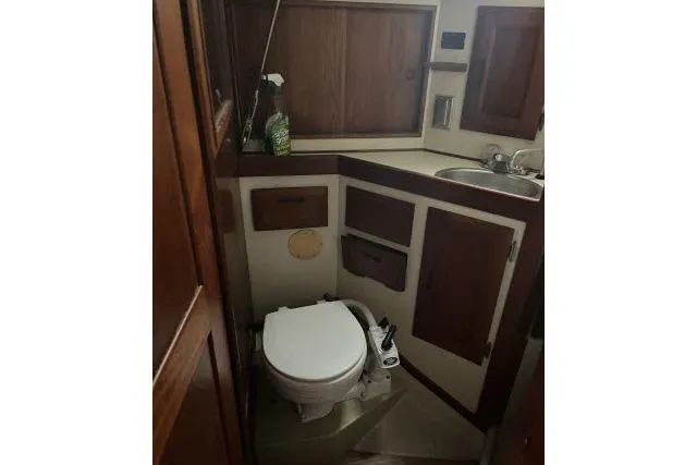 Slide: The Image of 1983 Ericson 381 yacht bathroom with wooden cabinets and compact toilet. - 15