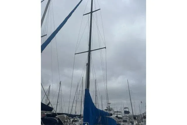 Slide: The Image of Sailboat with blue cover, Ericson 381, 1983 model, docked under cloudy sky. - 31