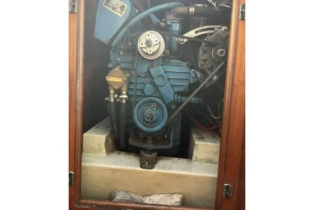 Slide: The Image of 1983 Ericson 381 engine compartment with visible blue machinery and wooden framing. - 33