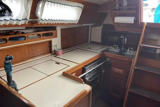Slide: The Image of 1983 Ericson 381 yacht interior kitchen with wood cabinetry and compact design. - 7
