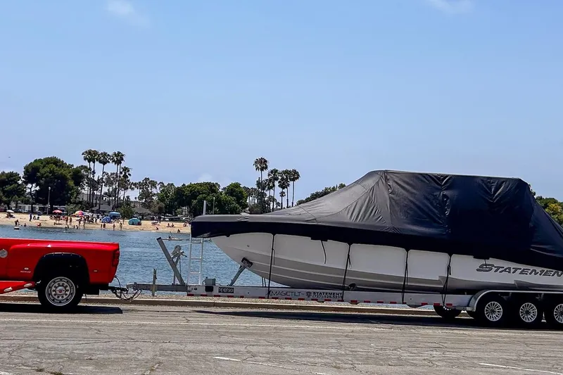 Slide: The Image of Red truck towing a covered 2026 Statement 350 Open boat near a beach. - 45