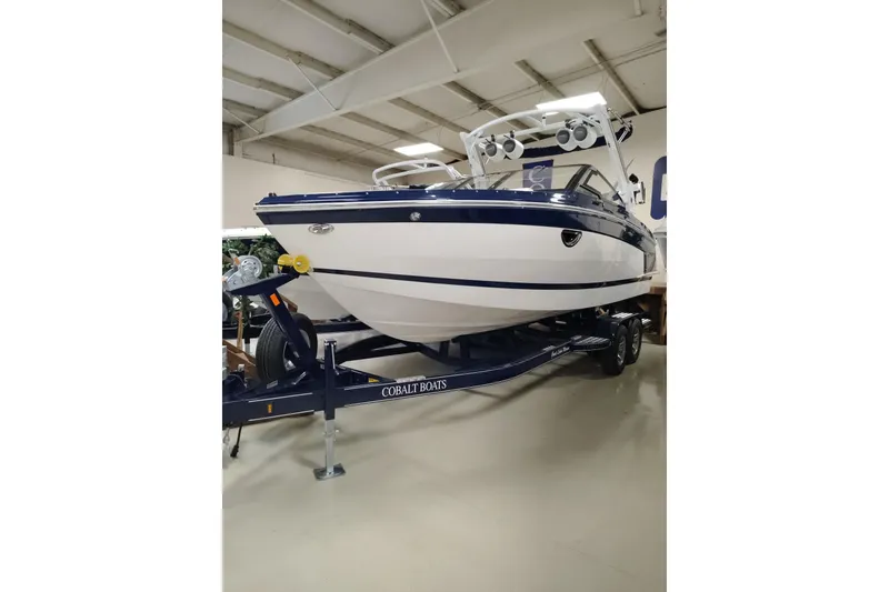 The Image of 2026 Cobalt R6 Surf boat on trailer in showroom, featuring sleek design and modern features. - 0