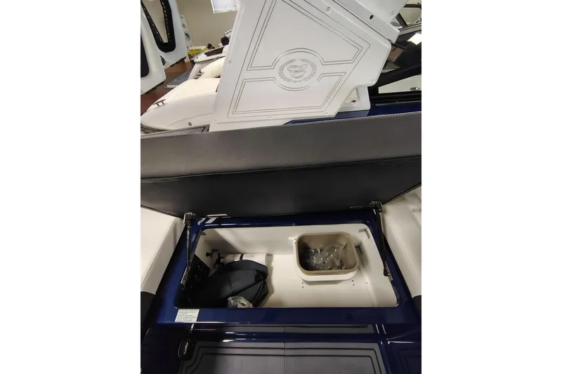 Slide: The Image of 2026 Cobalt R6 Surf boat interior storage compartment with open lid and visible accessories. - 12