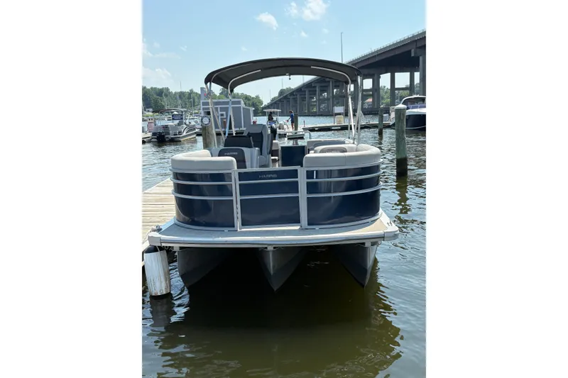 Slide: The Image of 2025 Harris Cruiser 230 pontoon boat docked at marina under clear sky. - 3