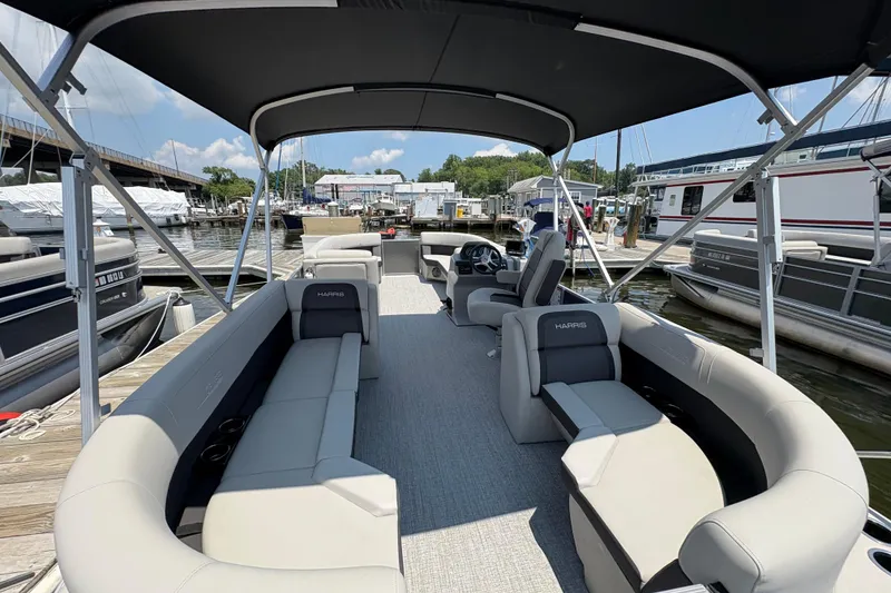 Slide: The Image of 2025 Harris Cruiser 230 pontoon boat with spacious seating at a marina. - 4