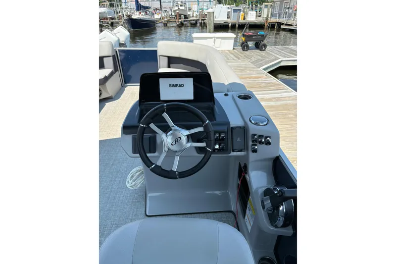 Slide: The Image of 2025 Harris Cruiser 230 boat helm with steering wheel and Simrad display at dock. - 7