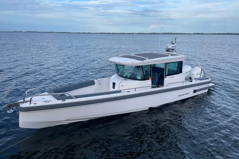 The Image of 2022 Axopar 28 Cabin boat on calm ocean waters under a cloudy sky. - 1