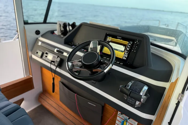 Slide: The Image of 2022 Axopar 28 Cabin boat dashboard with steering wheel and navigation system. - 11