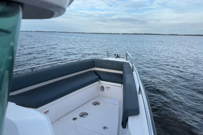 Slide: The Image of 2022 Axopar 28 Cabin boat with cushioned seating, on calm water under a cloudy sky. - 13