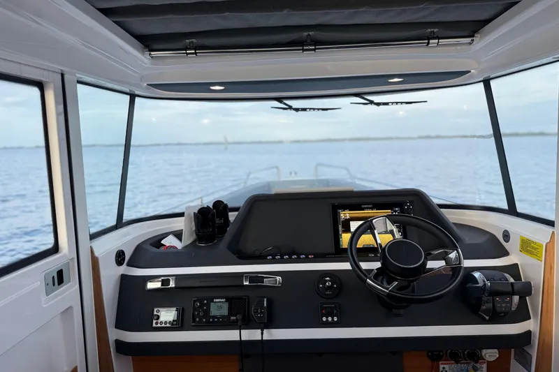 Slide: The Image of Interior view of 2022 Axopar 28 Cabin boat cockpit with steering wheel and navigation controls. - 15