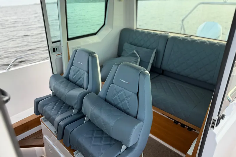 Slide: The Image of 2022 Axopar 28 Cabin interior with blue quilted seats and ocean view. - 18