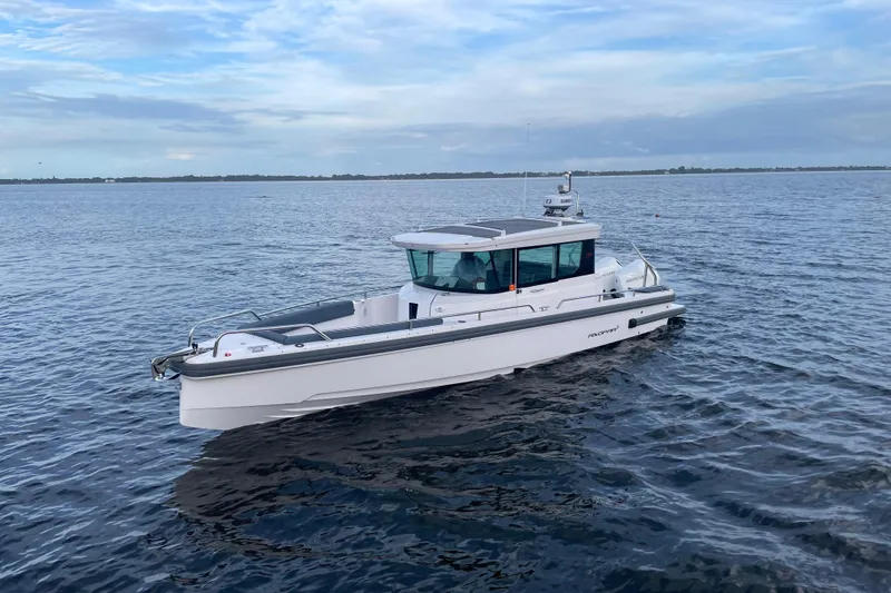 Slide: The Image of 2022 Axopar 28 Cabin boat cruising on open water under a cloudy sky. - 2