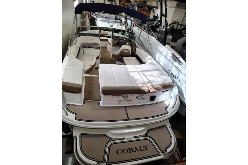Slide: The Image of 2016 Cobalt 220 boat interior with seating and helm, showcased in a showroom. - 7