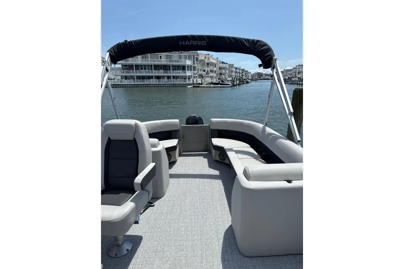 Slide: The Image of 2025 Harris Cruiser 230 pontoon boat interior with seating, on a calm waterway. - 4