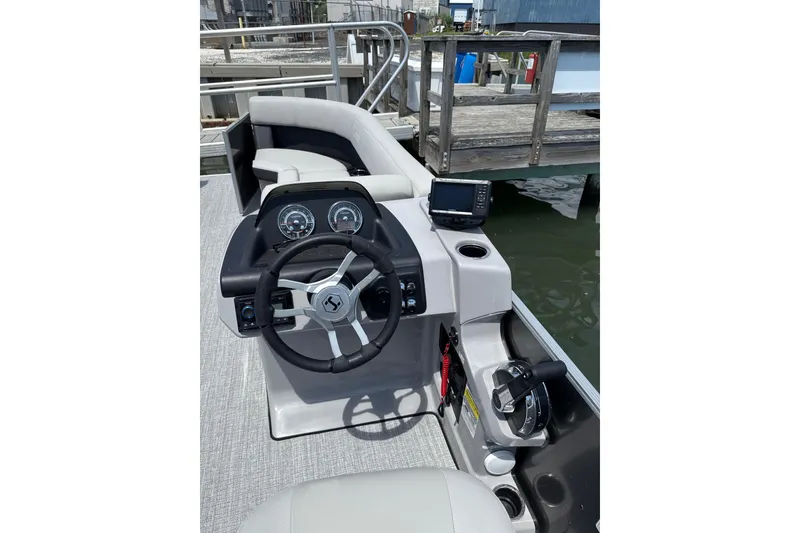 Slide: The Image of 2025 Harris Cruiser 230 boat dashboard with steering wheel and controls at dock. - 6