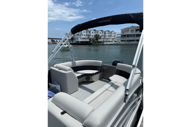 Slide: The Image of 2025 Harris Cruiser 230 pontoon boat with spacious seating on a sunny waterfront. - 8