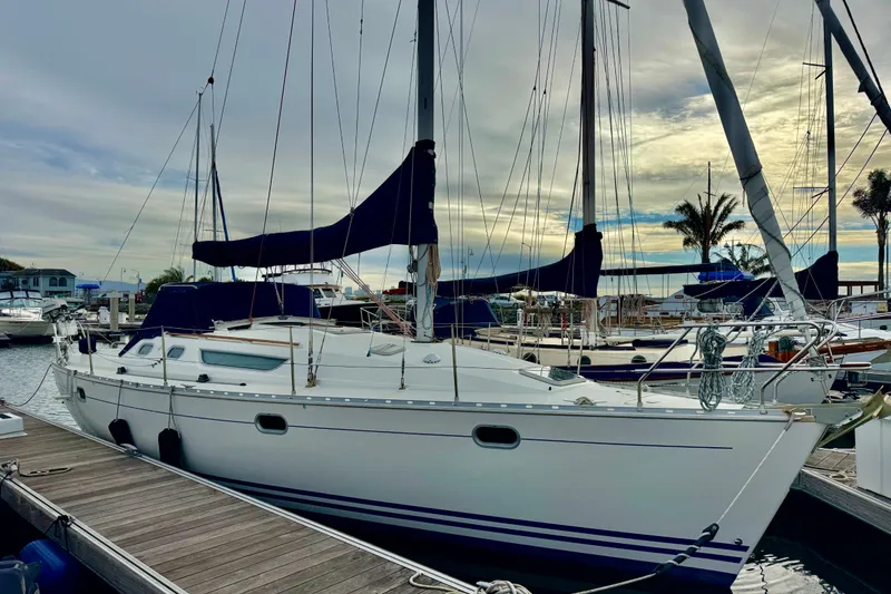 Slide: The Image of 1997 Jeanneau Sun Odyssey 36.2 sailboat docked in a marina, surrounded by other boats. - 1