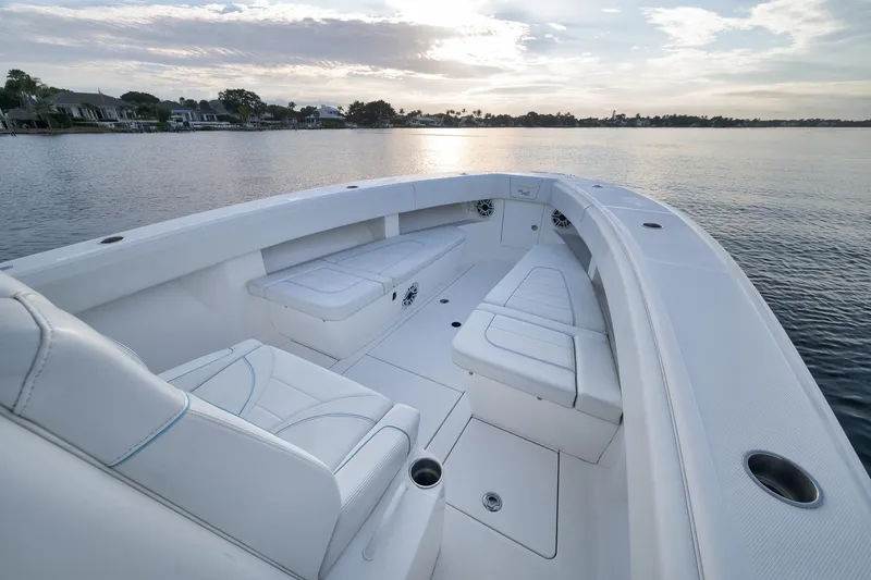 Slide: The Image of 2023 SeaVee 322Z boat interior with white seating, on calm water at sunset. - 14
