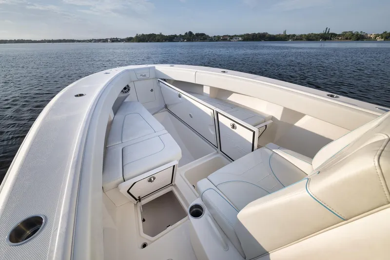 Slide: The Image of 2023 SeaVee 322Z boat interior with white seating and storage, on calm water. - 21