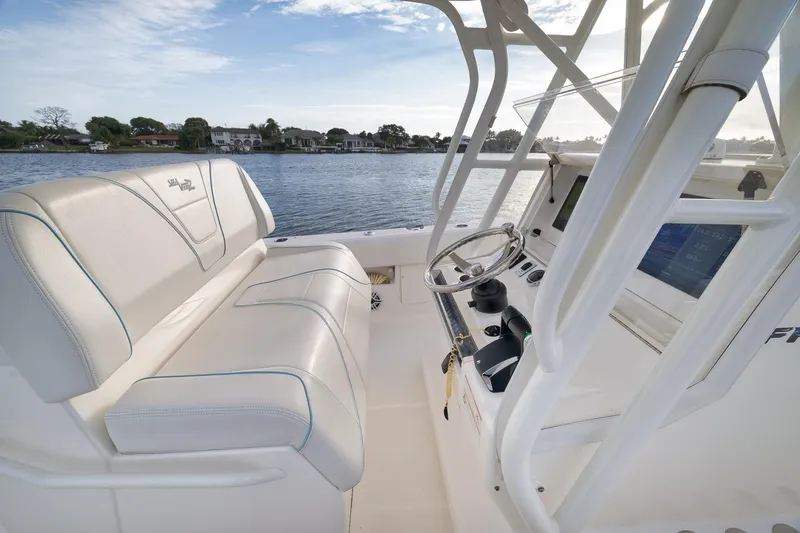 Slide: The Image of 2023 SeaVee 322Z boat interior with steering console and seating, on a calm waterway. - 34
