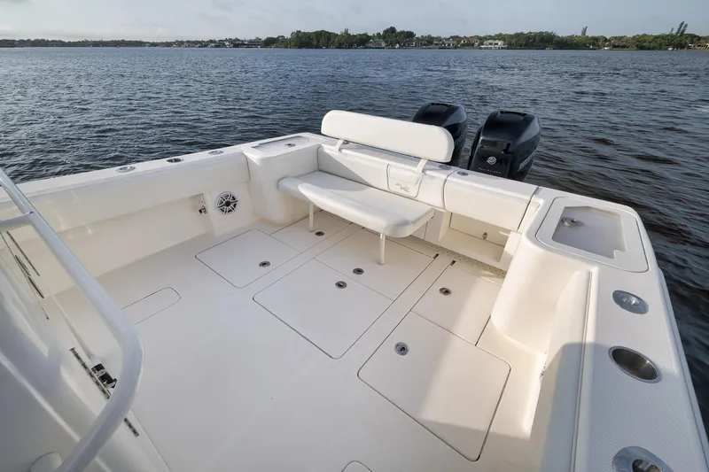 Slide: The Image of 2023 SeaVee 322Z boat deck with seating, storage, and twin engines on a calm lake. - 40