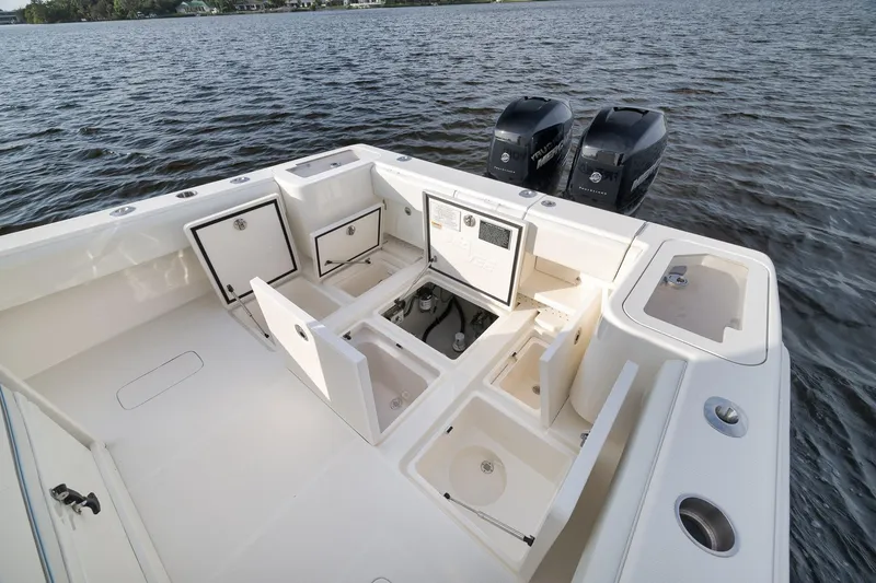 Slide: The Image of 2023 SeaVee 322Z boat with open storage compartments and dual engines on a calm lake. - 46