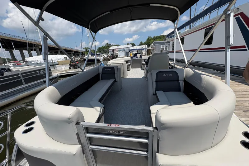 Slide: The Image of 2025 Harris Cruiser 230 pontoon boat with spacious seating and canopy, docked at marina. - 3