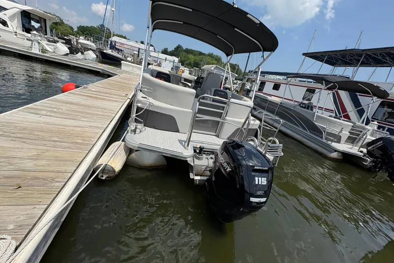 Slide: The Image of 2025 Harris Cruiser 230 pontoon boat docked at marina with Mercury 115 engine. - 7
