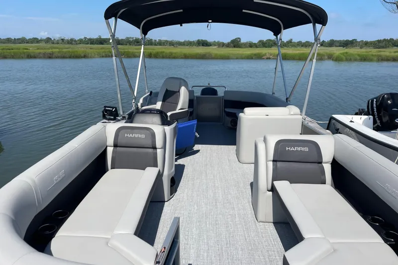 Slide: The Image of 2025 Harris Cruiser 230 pontoon boat with spacious seating on a calm river. - 4