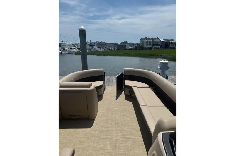 Slide: The Image of 2025 Harris Cruiser 230 pontoon boat interior with beige seating, docked by waterfront homes. - 3