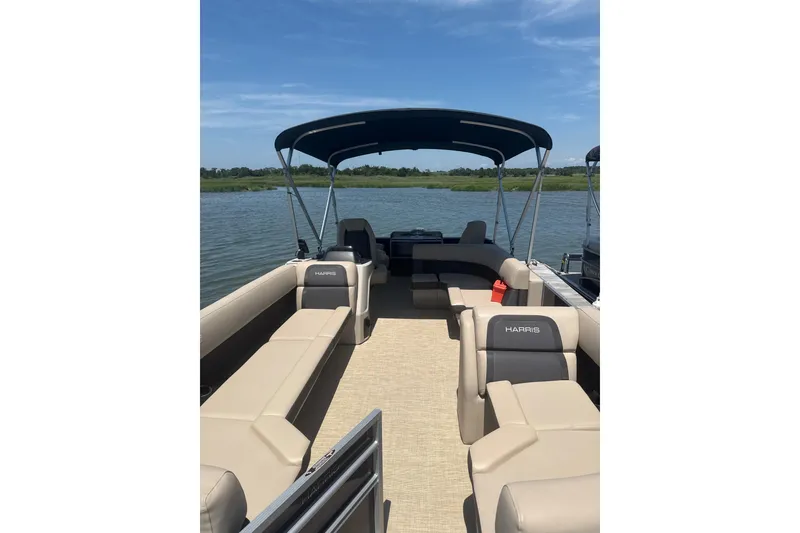 Slide: The Image of 2025 Harris Cruiser 230 pontoon boat with spacious seating on a sunny lake. - 4