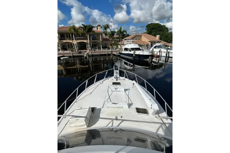 Slide: The Image of 1988 Ocean Yachts 48 Super Sport docked at marina, clear sky, waterfront homes. - 4