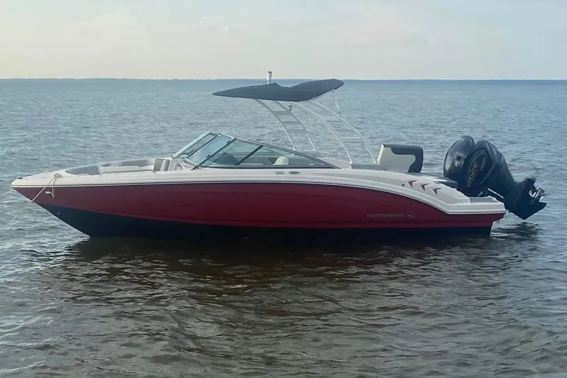 The Image of 2023 Chaparral 23 SSi OB boat with red hull on calm water. - 0