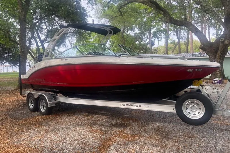Slide: The Image of 2023 Chaparral 23 SSi OB boat on trailer, parked under trees. - 2