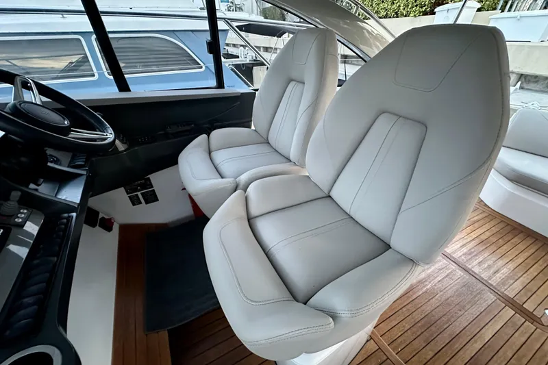 Slide: The Image of Luxurious 2021 Princess V40 yacht interior with elegant seating and wooden table, overlooking waterfront buildings. - 13