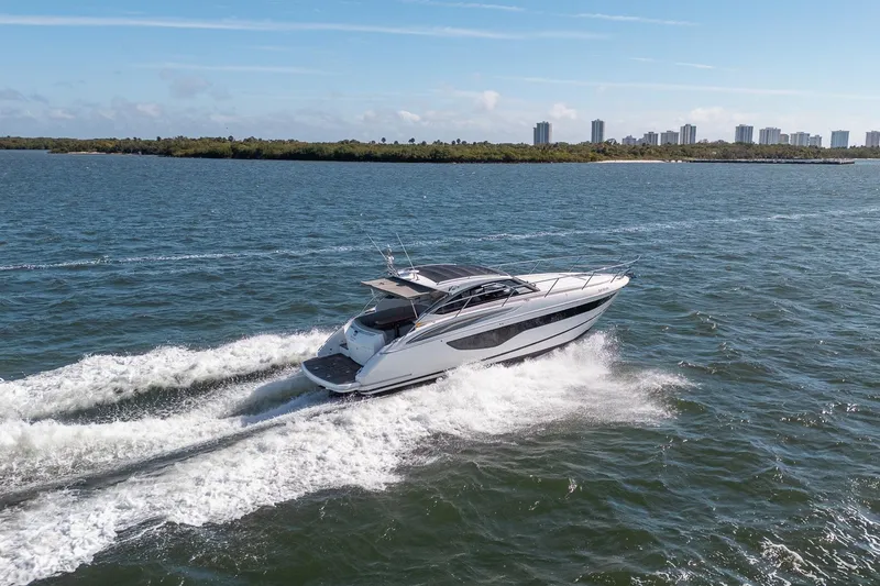 Slide: The Image of 2021 Princess V40 yacht cruising on open water with city skyline in background. - 58