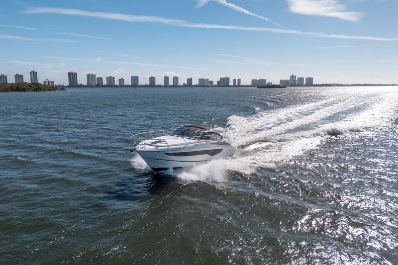 Slide: The Image of 2021 Princess V40 yacht cruising on open water with city skyline backdrop. - 59
