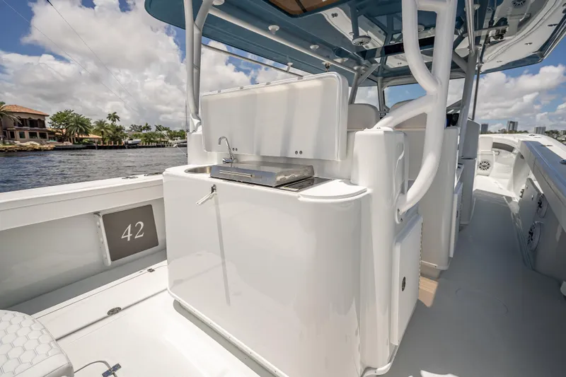Slide: The Image of 2025 Yellowfin 42 Offshore boat with outdoor kitchen, docked by waterfront homes. - 51